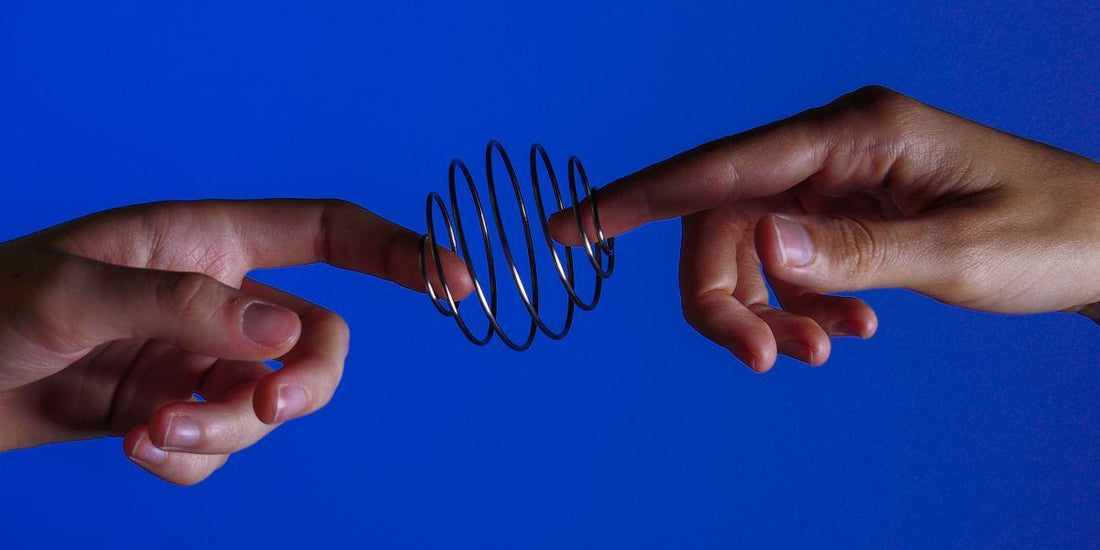 Handen spelen met metalen slinky speelgoed tegen blauwe achtergrond