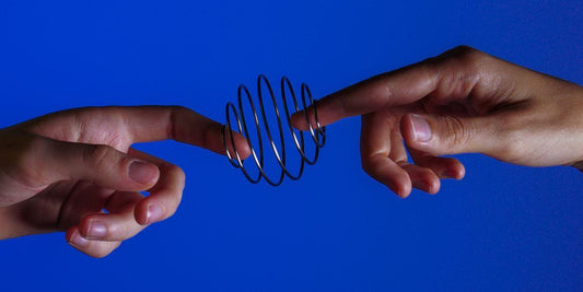Handen spelen met metalen slinky speelgoed tegen blauwe achtergrond