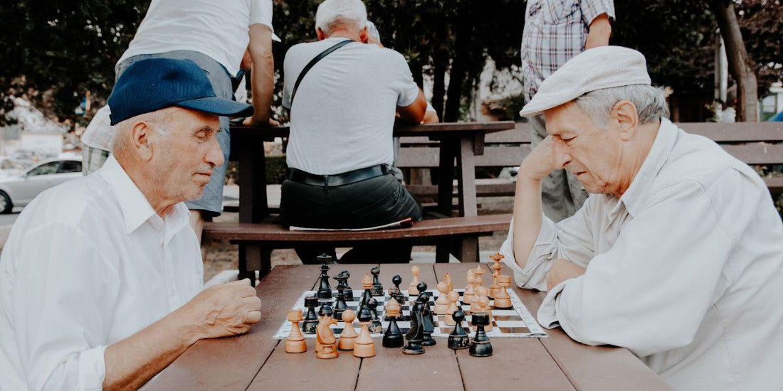 Ouderen spelen schaak op houten tafel in park, strategie spel voor jong en oud