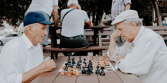 Ouderen spelen schaak op houten tafel in park, strategie spel voor jong en oud