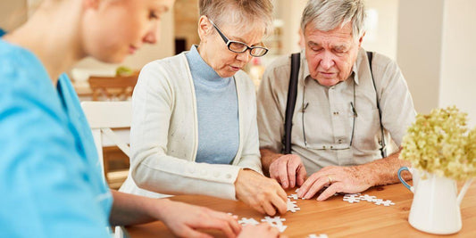 Oudere paar en jonge vrouw samen puzzelen aan houten tafel, gezellige familieactiviteit